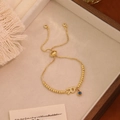 Dettaglio del bracciale Evil Eye dorato con ciondolo lettera R e cordino regolabile - Lettera R