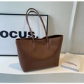 Dettaglio di una grande borsa tote marrone con texture in pelle e cuciture rifinite - Marrone