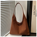 Detail view of brown suede tote bag with leather strap in soft natural window lighting - Brown