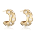 Macro view of gold-plated C-shape hoop earrings with white enamel heart patterns - White