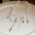 Primer plano de perlas barrocas y colgantes de estrellas plateadas en plato cerámico - Collar de Perlas de Estrella Plateada