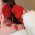 Dettaglio di grandi orecchini a fiore rosso in tessuto con lunghe nappe e nastri di seta - Rosso Puro