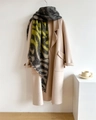 Détail d'une écharpe léopard à franges avec un manteau beige sur fond de studio photo - Motif Noir Jaune Gris