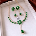 Detailed macro view of the gold flower pendant necklace and earrings with emerald gems - Gold-Green