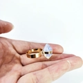 Golden wide band ring featuring a hexagonal white crystal stone on a palm display - Opal