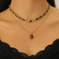 Mehrlagige Goldkette mit Tigerauge-Anhänger und Lederband auf schwarzem Spitzenkleid - Helles KC-Gold (Doppelschicht-Set)