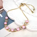 Detail of pink enamel evil eye charm and clear zircon stones on gold adjustable bracelet - Pink