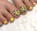 Primo piano di unghie finte piedi gialle leopardate con macchie blu su marmo - FW112