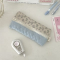 Détail d'une trousse à fleurs et matelassée avec fermeture éclair sur un bureau - Tissu Gaufré Coeur Bleu Clair