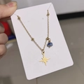Dettaglio della collana bussola dorata con perla blu e ciondolo a stella su cartoncino bianco - Stile Pietra Naturale Stella a Otto Punte