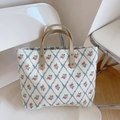 Dettaglio della borsa floreale con motivi a rombi blu e manici in pelle marrone - Piccoli Fiori a Rete Blu