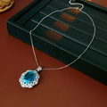 Vista detallada del collar de flor con gema azul ovalada en bandeja de terciopelo - Plata-Azul