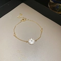 Detailed shot of gold-plated bamboo bracelet featuring a sparkling zircon flower pendant - Round Floral Pendant Style