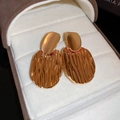 Detailed close-up of golden wavy metallic earrings resting inside a premium jewelry box - Oval Pleated Real Gold Plated Style (17#)