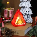 Red Christmas lantern with Christmas tree silhouette and warm LED glow on rustic books - Red Christmas Tree