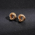 Detail shot of golden multi-loop intertwined knot earrings on textured grey background - Gold