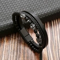 Dettaglio del bracciale multistrato in pelle nera e corda con ciondoli a teschio in metallo - Nero + Ossidiana