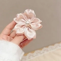 Pink satin flower hair clip with pearl center detail held against lace background - Ribbon Cherry Blossom Bead