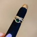 Macro shot of tiered gold ring with oval emerald gemstone and pavé-set diamonds - Gold-Green