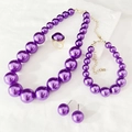 Detailed macro view of purple pearl necklace set with gold hardware on white surface - Purple