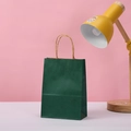 Close-up of a dark green kraft paper gift bag with natural woven rope handles on a surface - 15*11*6 / Dark Green