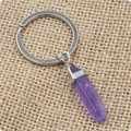 Dettaglio di un portachiavi in cristallo esagonale viola su sfondo di iuta ruvida - Ametista