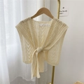 Beige knitted openwork shawl cardigan tied at front on a golden hanger with white curtains - Cream