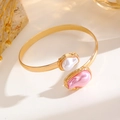 Nahaufnahme des goldenen Armreifs mit weißen und rosa Barockperlen im Sonnenlicht - Armreif (0323) / KC Gold