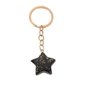 Detail of star-shaped keychain with black translucent resin and gold foil flakes - Star