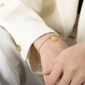 Bracciale a catena serpente dorata con ciondolo a moneta su un polso da donna - Oro