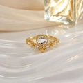 Macro detail of a gold heart-shaped ring with micro-pave crystals on a white plate - Clear Heart Exquisite Design (JZ0139)
