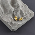 Dettaglio di orecchini placcati oro 18k con zircone rosa su una roccia grigia - Base Argento - Zircone Giallo