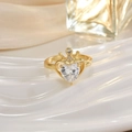 Macro view of a gold heart-shaped gemstone ring with a crown design on white ceramic - Heart Crown Open Style (JZ0136)