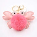 Détail d'un porte-clés crabe rose en peluche avec pompon doux et crochet en métal doré - Rouge Pastèque
