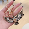 Golden eagle wings keychain with amber teardrop gemstone and grey cat-eye stones - Champagne