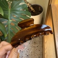 Detail of amber tortoiseshell claw clip held in hand showing large resin hair grip design - Large / Americano