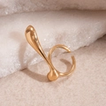 Detailed view of an irregular golden geometric ring set against a natural raw stone background - Gold