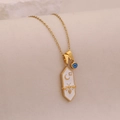 Detailed close-up of a gold hexagonal bee pendant with moon and stars on a white enamel base - White