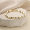 Detail of gold beads and white pearls bracelet draped over decorative white stones - 6mm/4mm Copper Beads + 6mm Imitation Pearls