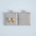 Detail of floral champagne gold stud earrings with pearls on gray velvet display stands - Gray