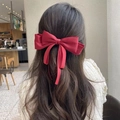Elegant red oversized ribbon bow hair clip accessory worn on long dark wavy hair - Red