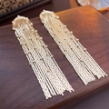 Detailed view of long gold tassel earrings with shimmering crystals on a wooden tray - Gold U-shape Tassel (4#)
