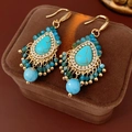Dettaglio macro di orecchini boho con turchese, nappe di perline blu e ganci dorati - Ganci per orecchini / Blu
