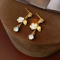 Primer plano detallado de pendientes de flores bañados en oro sobre joyero de terciopelo - Dorado (Pin de plata bañado en oro real)