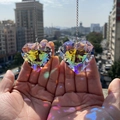 Close-up of hand holding two heart-shaped K9 crystal suncatchers with rainbow reflections - Heart 45mm
