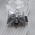 Porte-clés nœud argenté avec pendentif cœur métallique sur un fond minimaliste chic - Boucle Ronde / Argenté