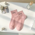 Pink crew socks with black SMILE embroidery and ribbed cuffs in a minimalist setting - One Size / Pink