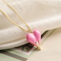 Macro shot of a gold chain necklace featuring a 3D pink heart pendant with gold drip detail - Pink