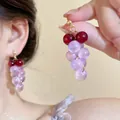 Détail de boucles d'oreilles perles en forme de raisin violet portées sur l'oreille - Style forme raisin rouge violet
