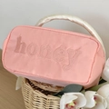Vue détaillée d'une trousse de maquillage rose en nylon avec broderie honey et satin - Rose